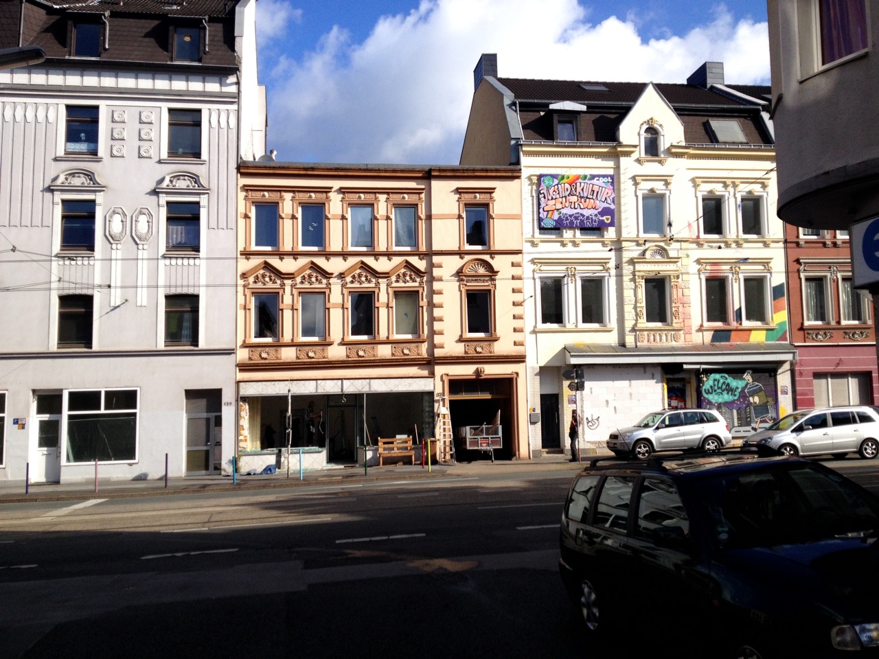 Straßenzug mit mehrstöckigen Gründerzeitbauten unterschiedlicher Fassadengestaltung und parkenden Autos.