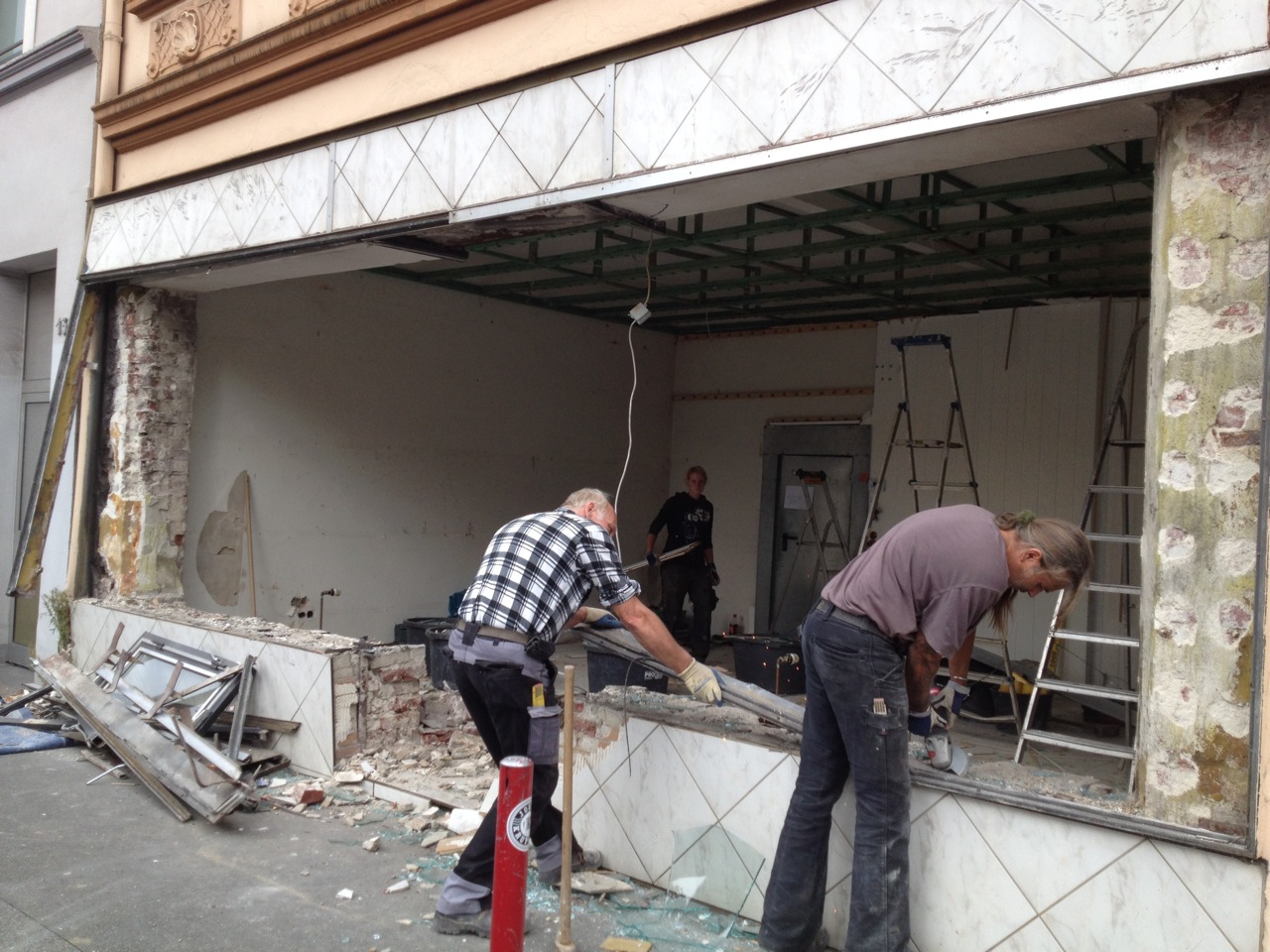 Arbeiter demolieren die Fassade eines leerstehenden Ladengeschäfts in der Stadt.