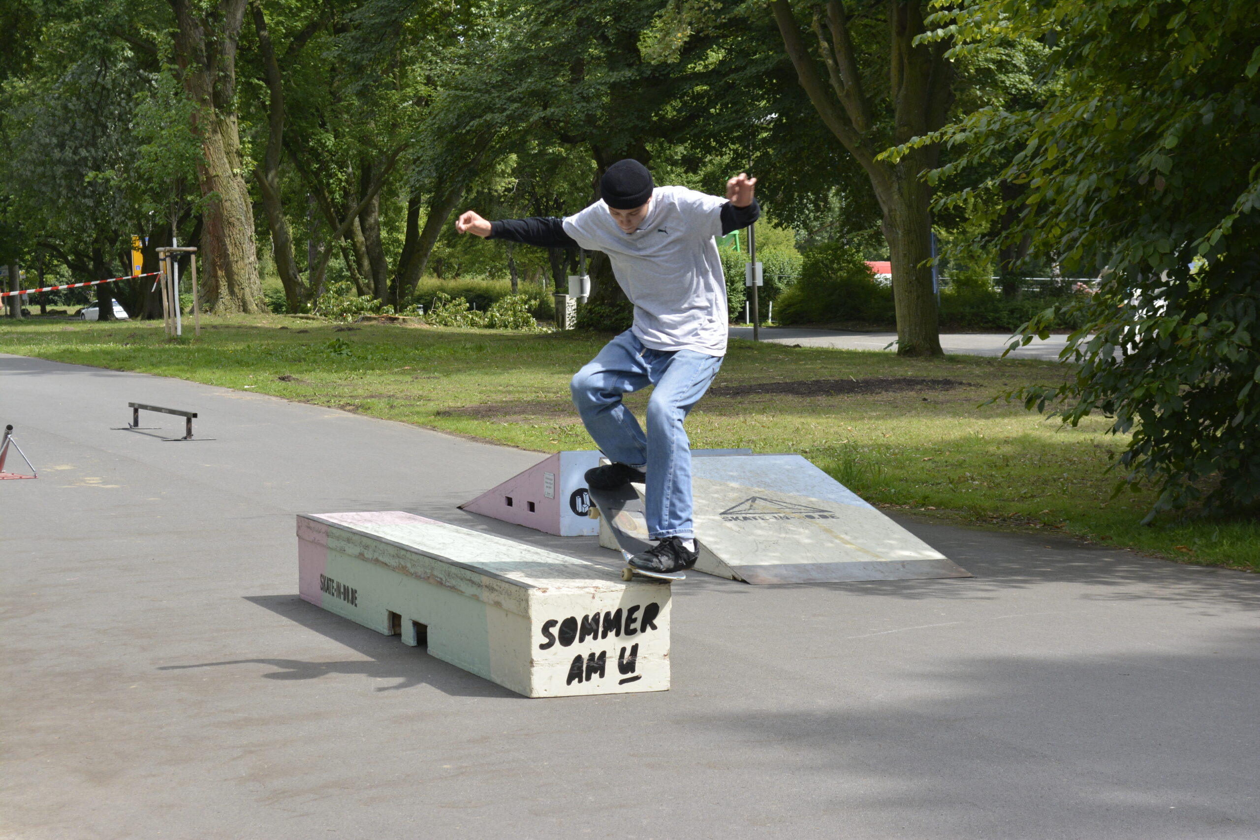Ein Skateboarder führt einen Trick auf einer Skate-Rampe in einem Park auf.