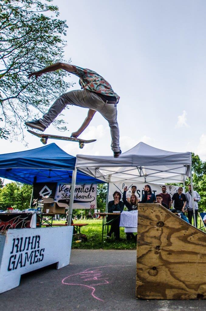 Skateboarder springt über Rampe bei Ruhr Games Event mit Publikum und Zelten.