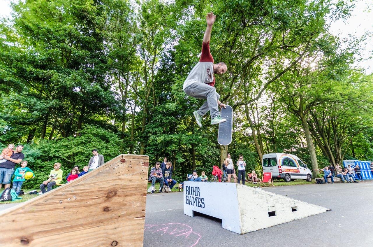 Skateboarder springt auf Rampe vor Zuschauern bei Ruhr Games Event im Park.