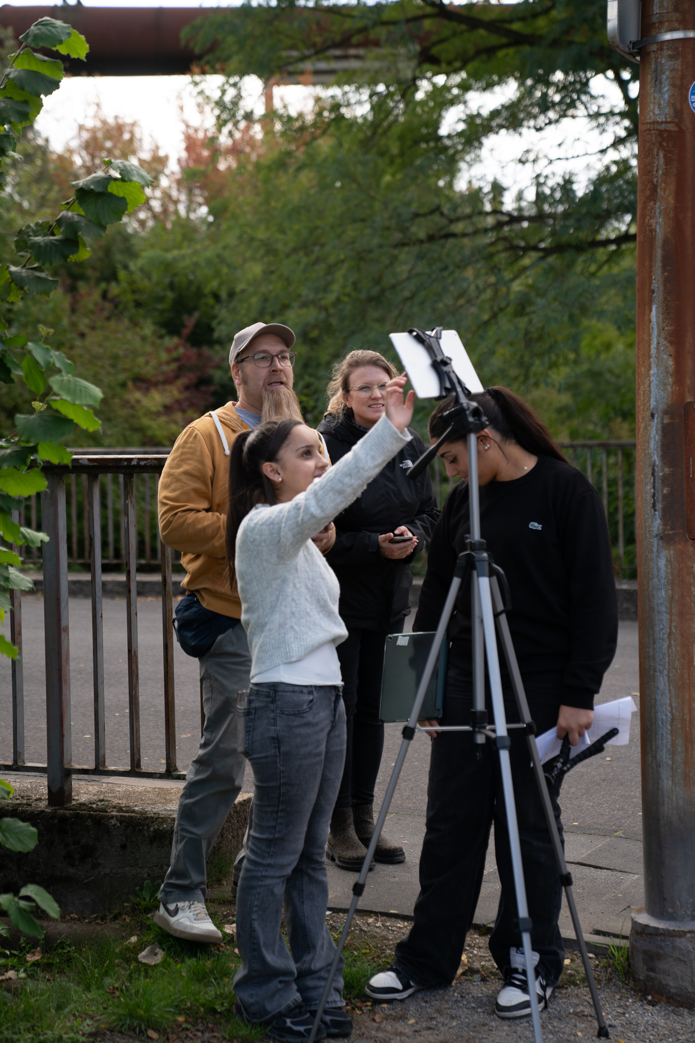 Fünf Personen bedienen gemeinsam eine Filmkamera auf Stativ in urbaner Umgebung.