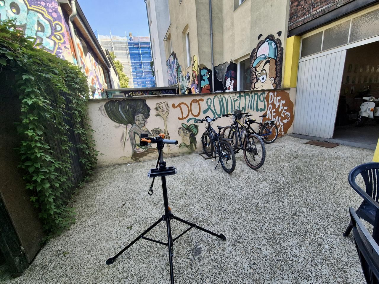In einem Innenhof steht eine Fahrradwerkstatt neben buntem Graffiti an der Wand.