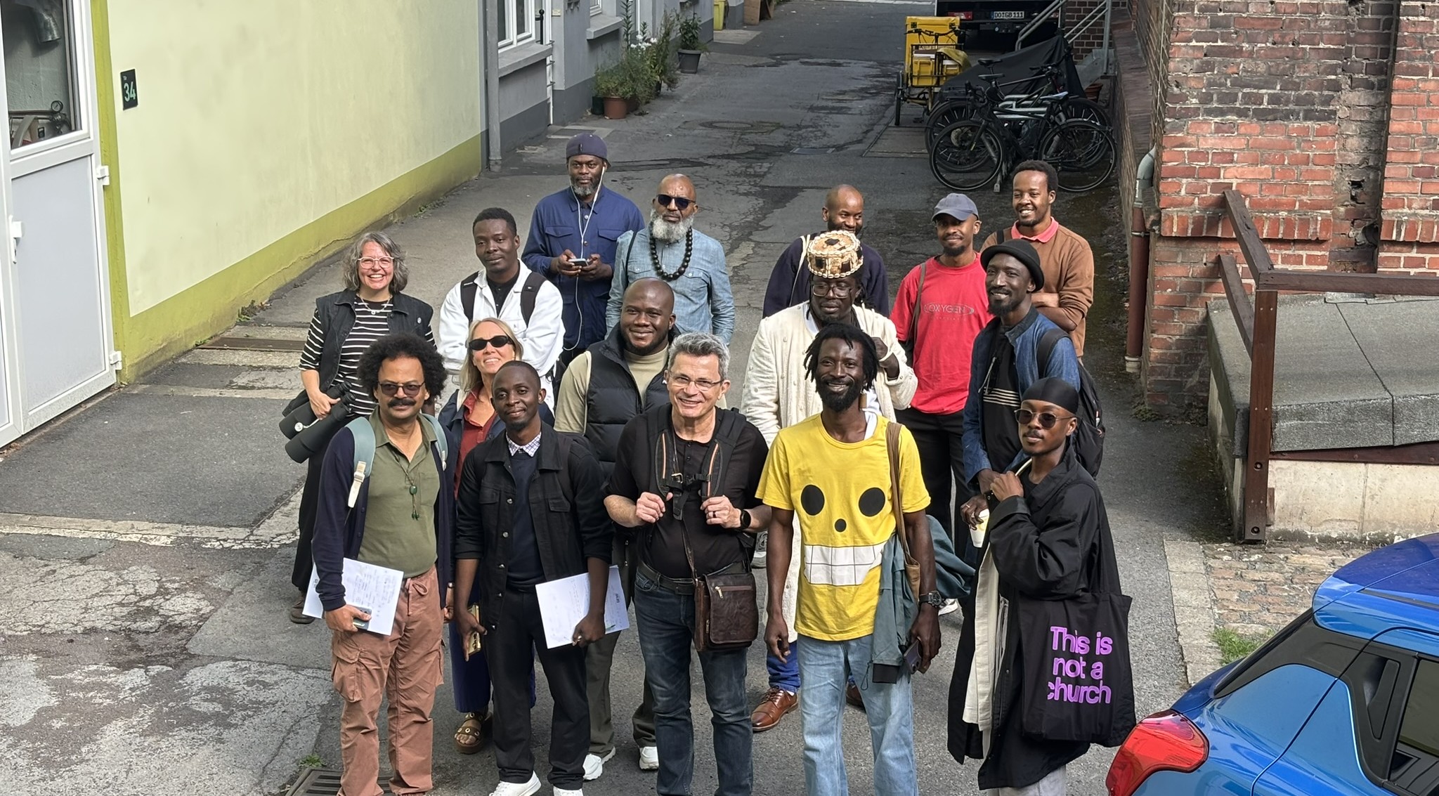 Etwa 20 Menschen verschiedener Herkunft stehen zusammen in einer Gasse für ein Gruppenfoto.