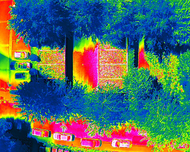 Wärmebild einer Straße mit parkenden Autos und Gebäuden in Infrarotdarstellung.
