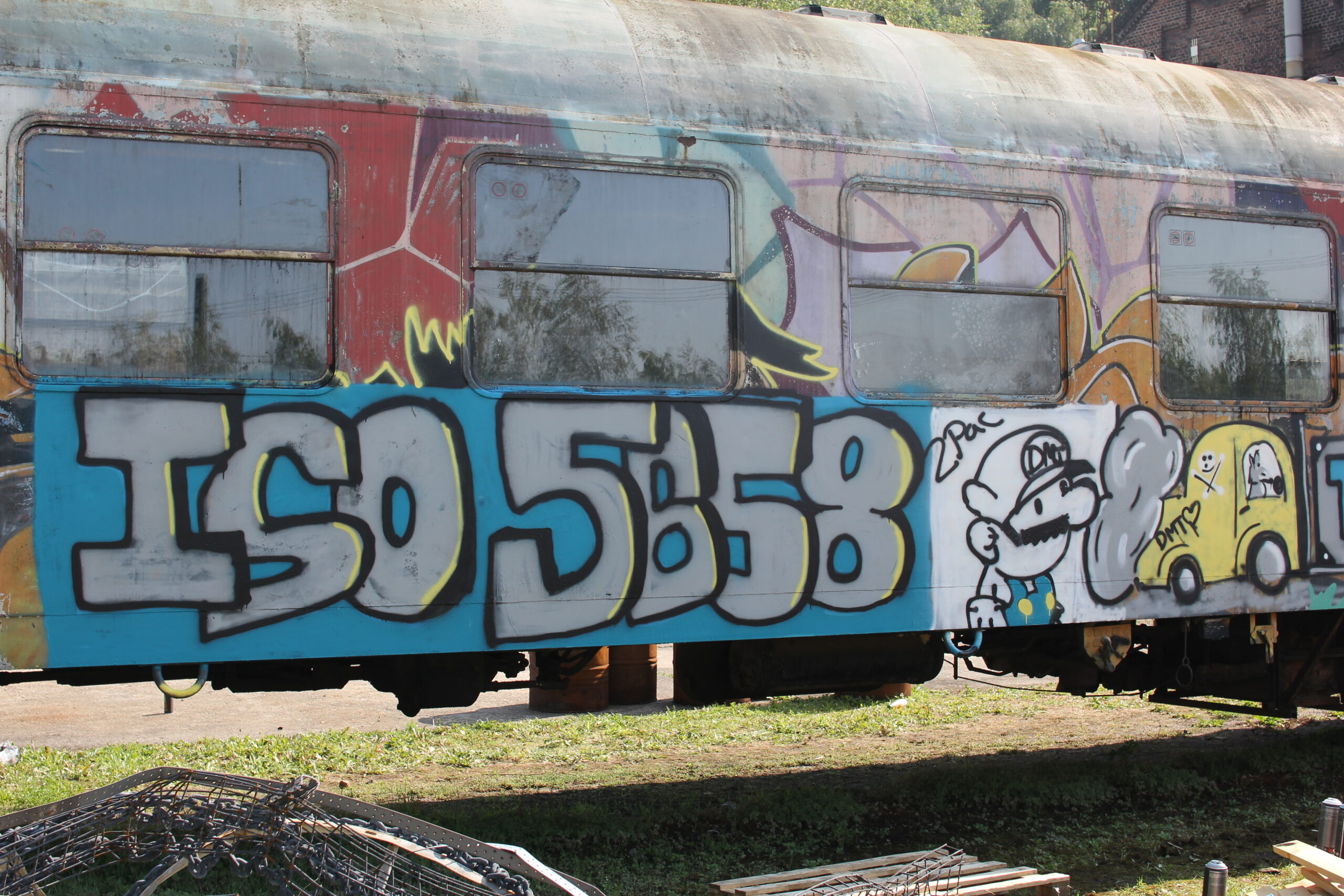 Graffiti-besprühter Eisenbahnwaggon mit großen blauen Buchstaben und Cartoon-Figuren.