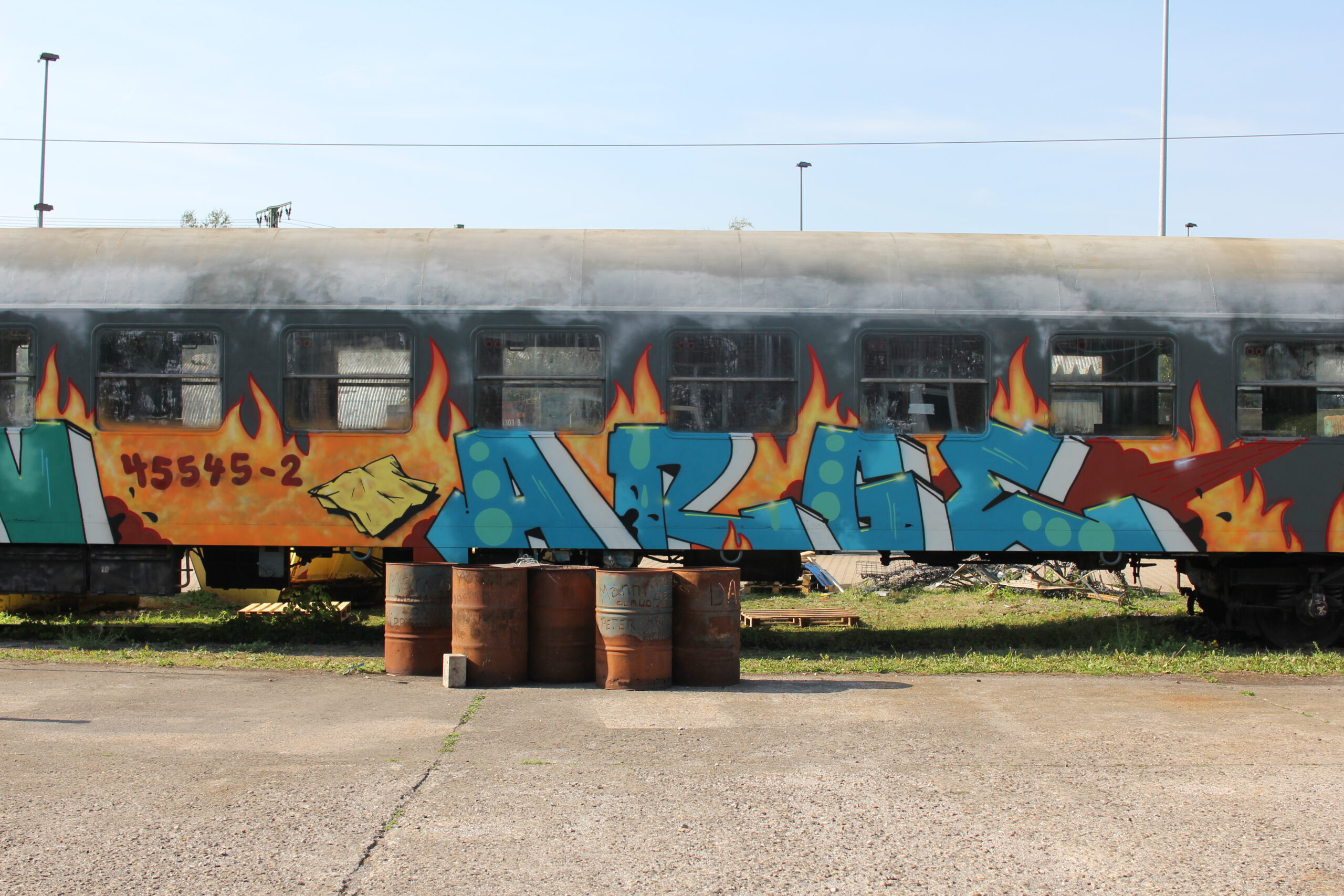 Stillgelegte Eisenbahnwagen mit farbigem Graffiti-Kunstwerk zeigen Flammen und abstrakte Formen.