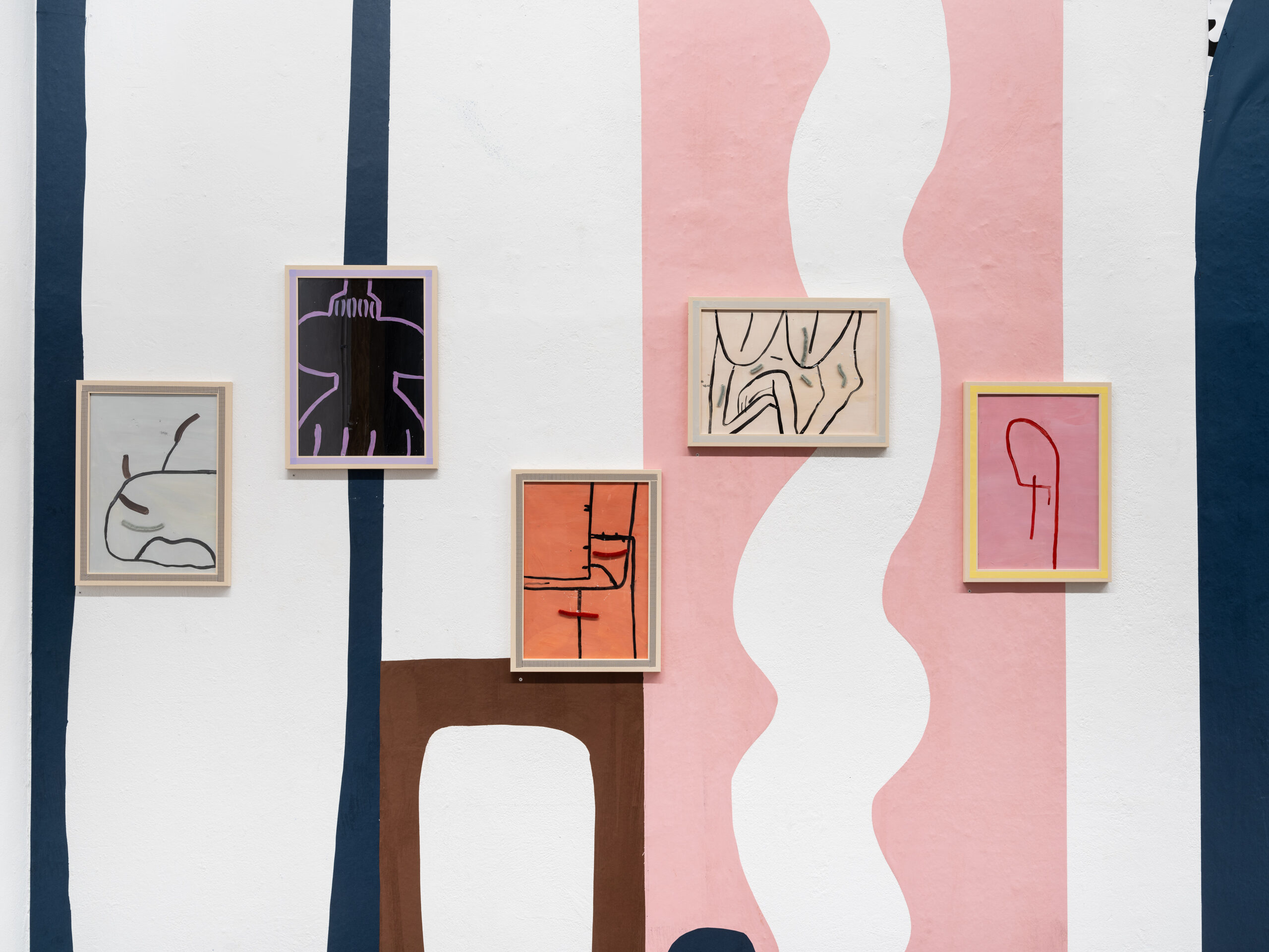 Fünf abstrakte Kunstwerke in Rahmen an einer farblich gestalteten Wand.