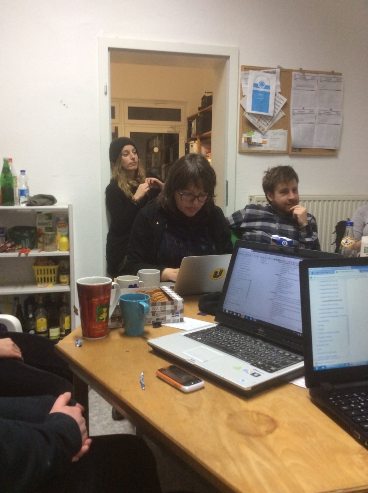 Vier Personen arbeiten an Laptops und Dokumenten an einem Tisch in einem Büro.