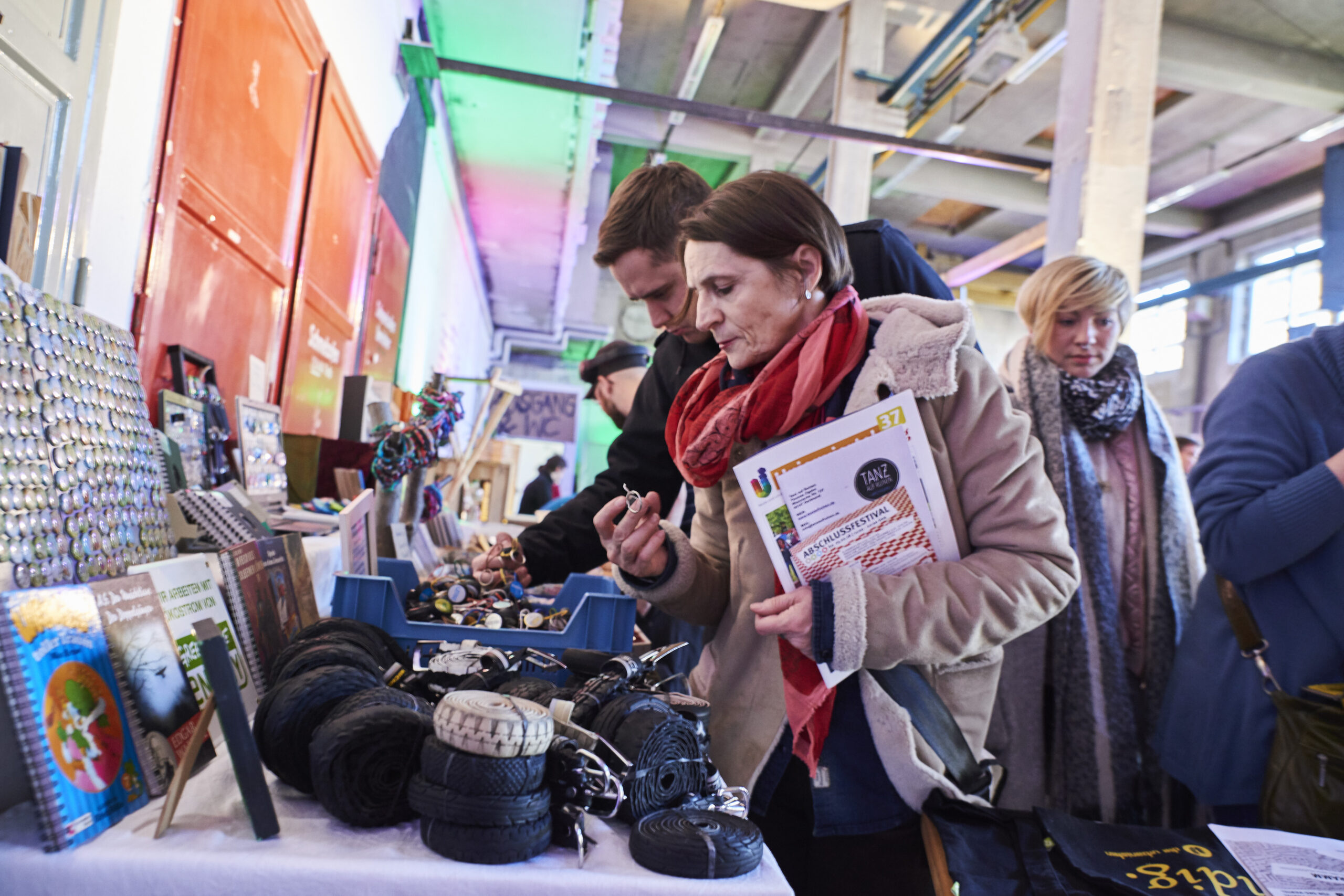 Besucher betrachten handwerkliche Produkte und Kunsthandwerk an einem Ausstellungsstand in einer Halle.