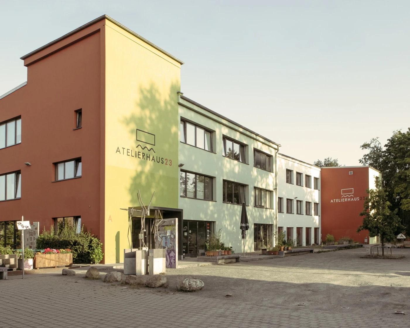 Moderne Gebäudekomplexe mit farbigen Fassaden in Rot, Gelb und Weiß bilden einen Platz.