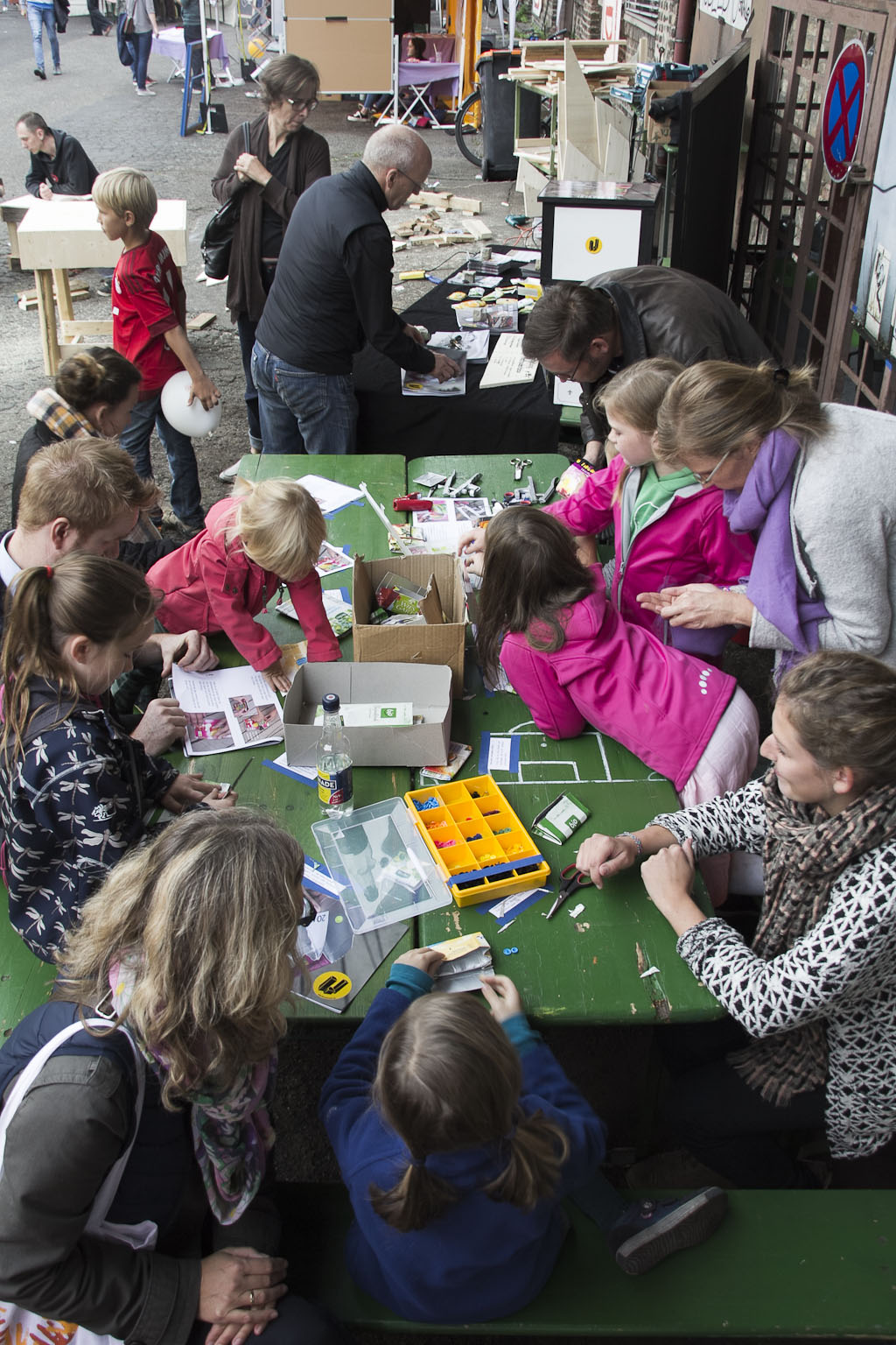 Kinder und Erwachsene beteiligen sich an einem interaktiven Workshop an einem grünen Tisch im Freien.
