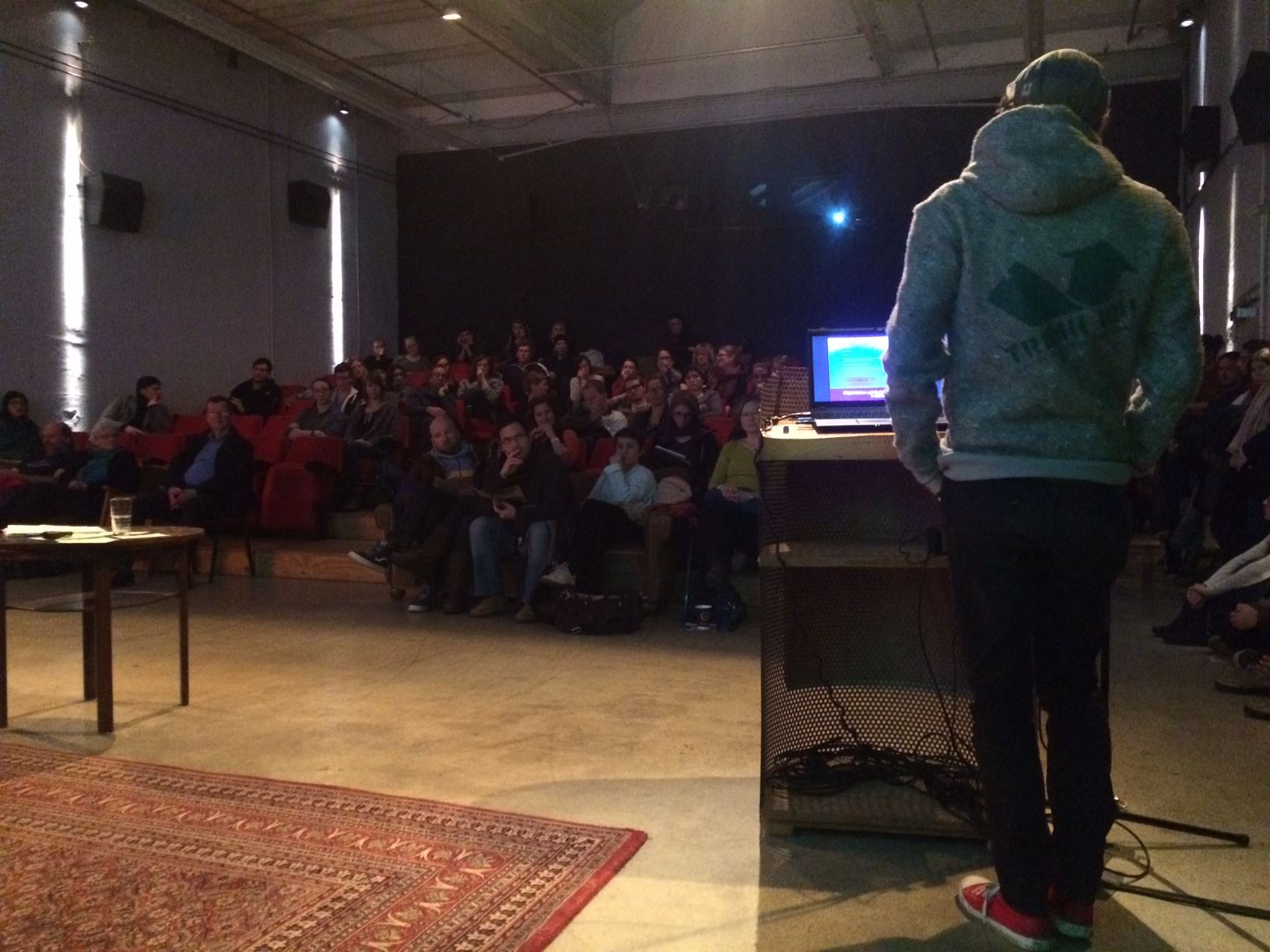 Präsentation vor Publikum in einem Veranstaltungsraum mit Laptop und Beamer.