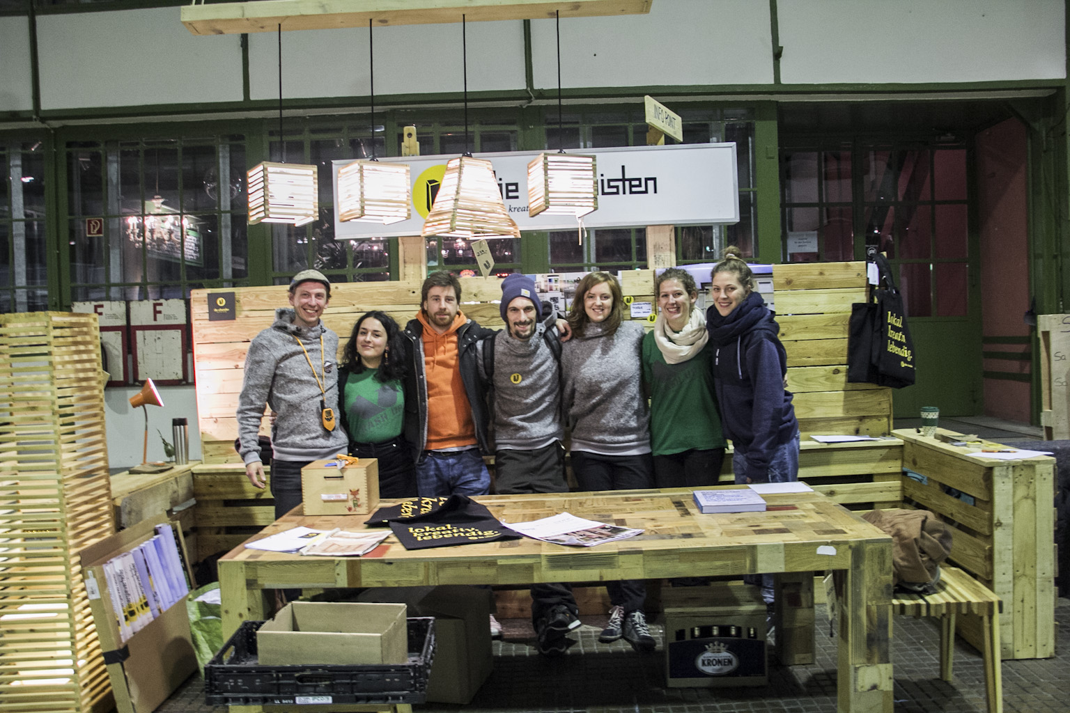 Sechs Personen stehen vor einem Holztisch in einem Workshop-Raum und blicken in die Kamera.