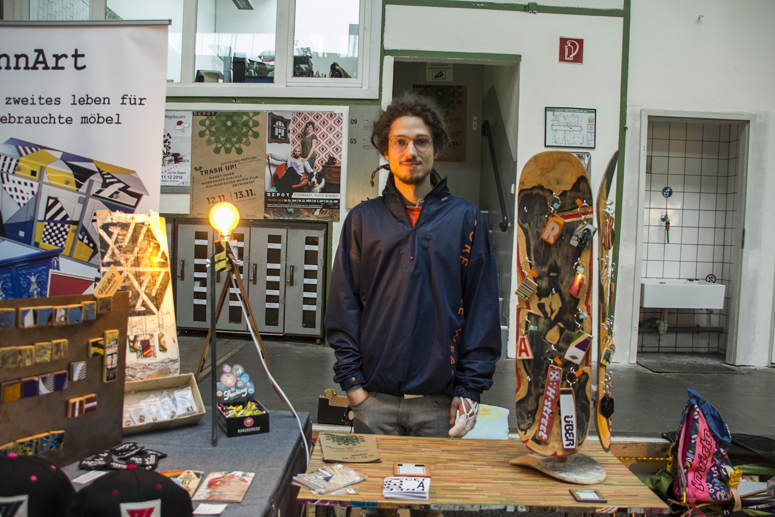 Mann in dunkler Jacke präsentiert in Werkstatt Skateboard-Designs und urbane Kunstobjekte.