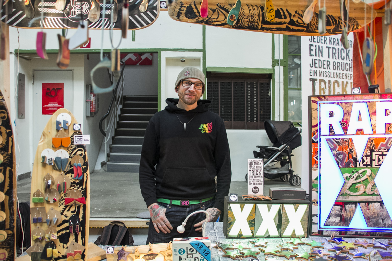Mann in Skatepark-Shop präsentiert Skateboard-Equipment und Streetwear-Produkte.