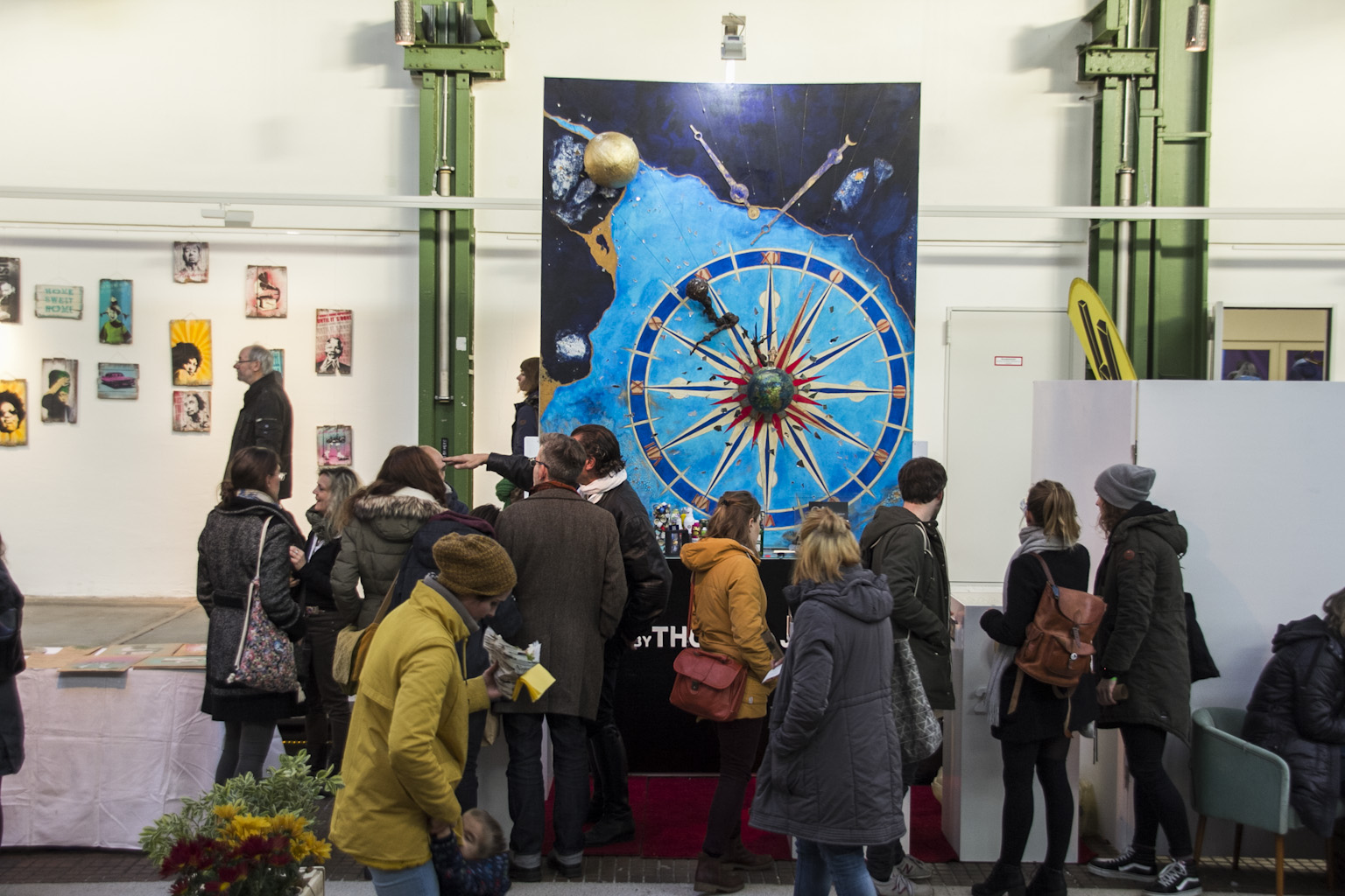 Besucher betrachten großformatige Kunstwerke in einer Ausstellungshalle mit industrieller Architektur.