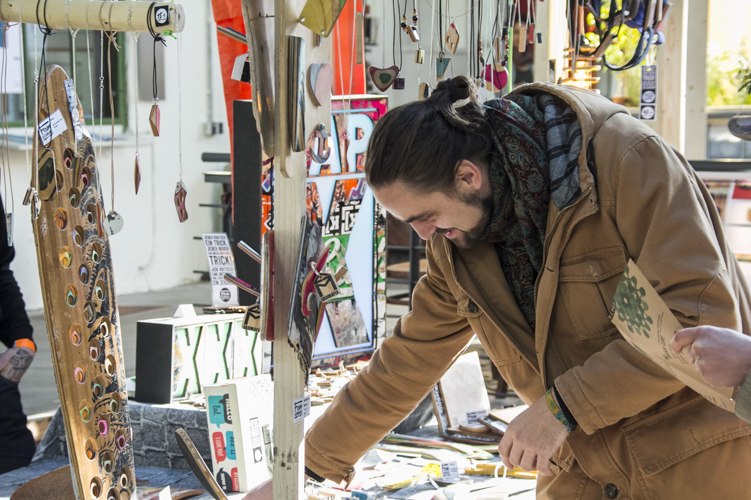 Eine Frau betrachtet und bearbeitet ein dekoratives Holzbrett auf einem Marktstand mit Kunsthandwerk.