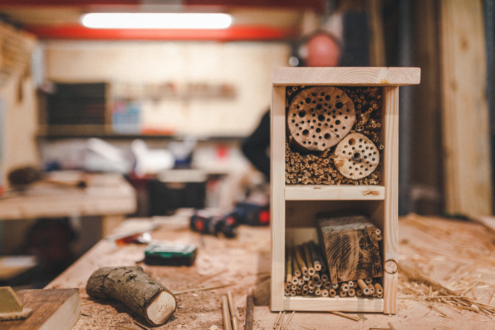 Insektenhotel aus Holz mit verschiedenen Materialien in einer Werkstatt.